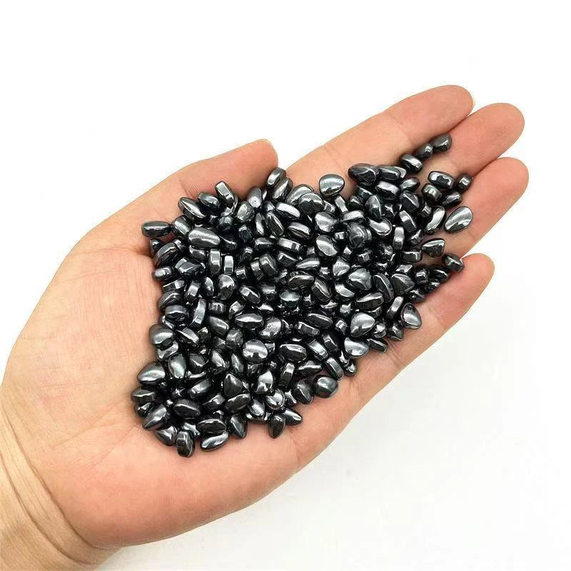 A hand holds a pile of black stone cobblestone set for DIY crafts and decoration.