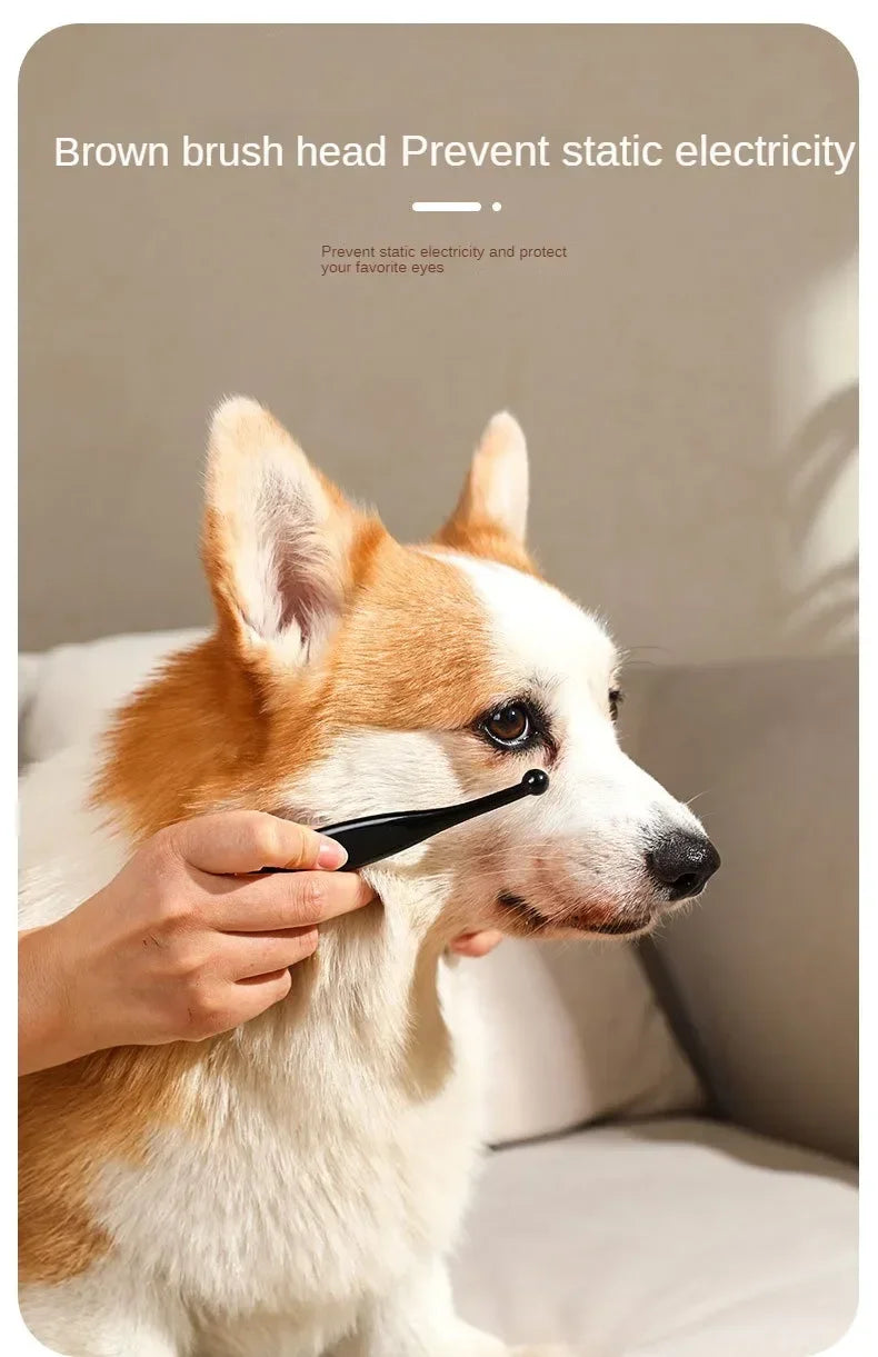 A hand holds a brown brush head designed to prevent static electricity, positioned near a dog's face.