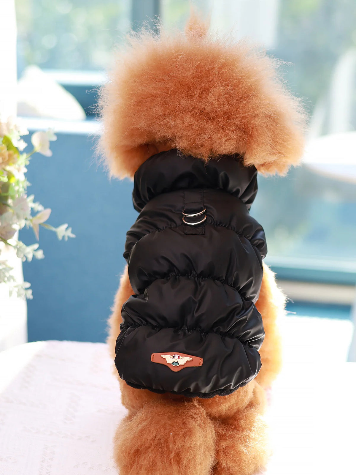 A fluffy orange dog jacket with a black quilted vest featuring a leather patch.