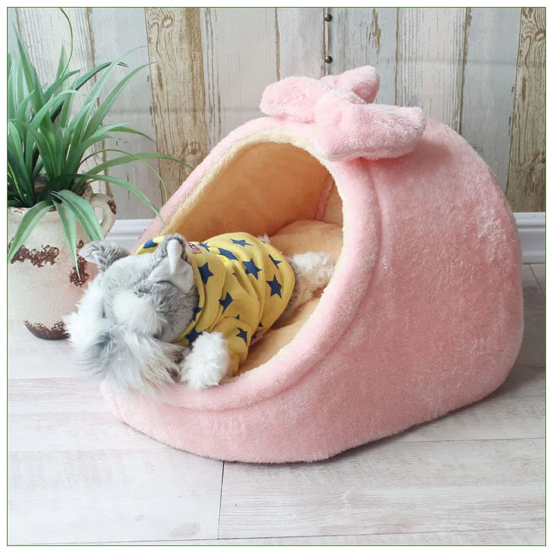 A pink, fluffy pet bed shaped like a cave, with a small dog resting inside.