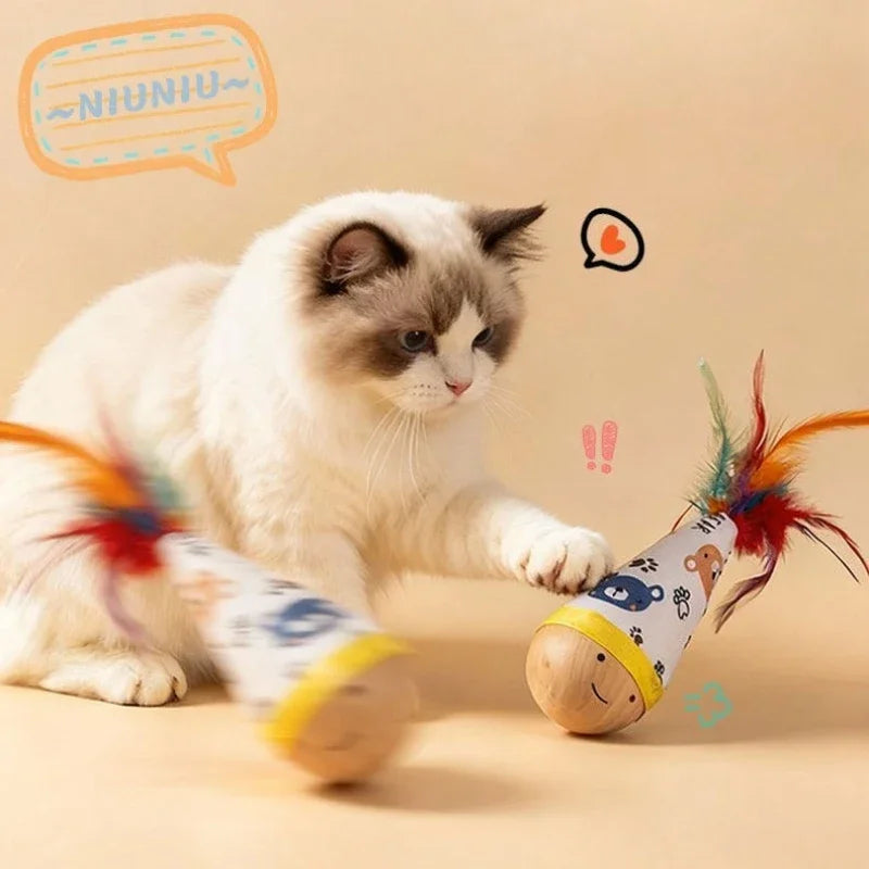 A fluffy white and gray cat is interacting with an interactive wobble toy featuring colorful feathers.