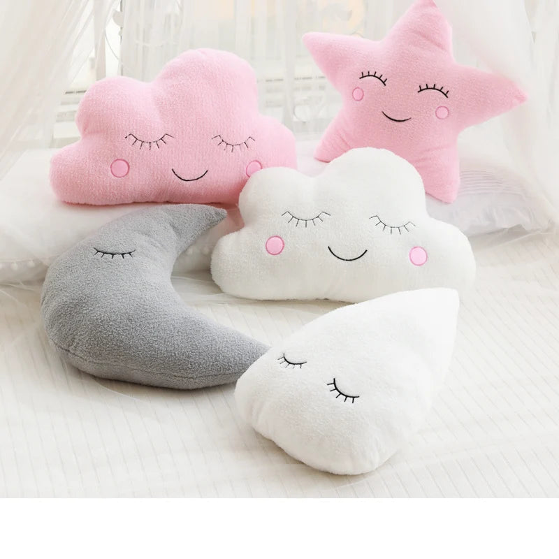 A collection of pink, white, and gray cloud and star-shaped plush pillows.