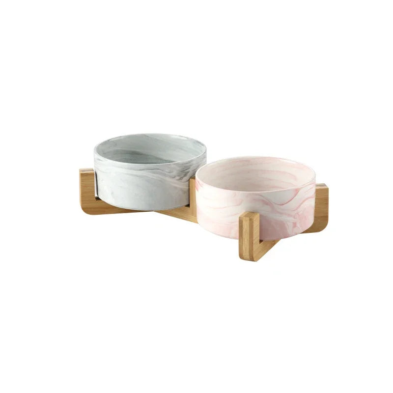 A set of two marbled ceramic pet bowls with a wooden stand.