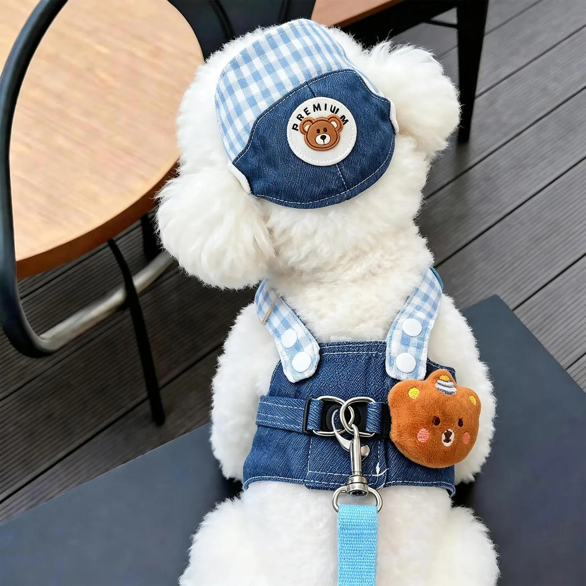 A fluffy white dog toy wearing a denim harness, matching sun hat, and leather collar.