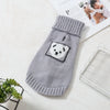 A gray knitted pet sweater with a white panda face design lying on a white surface.