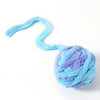 A fluffy light blue plush toy ball with a long, curved tail.