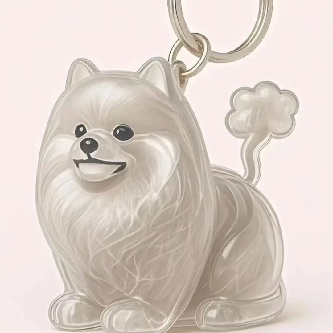 Figurine brillante et claire d'un chien blanc duveteux, accrochée à un anneau de clé en argent.