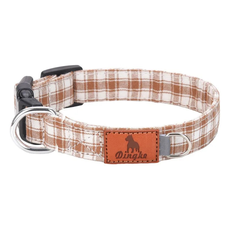 A brown and white plaid polyester dog collar with a silver buckle and an orange leather tag.