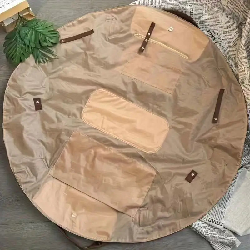 A tan foldable travel organizer bag with a matching picnic mat laid out on a dark surface.