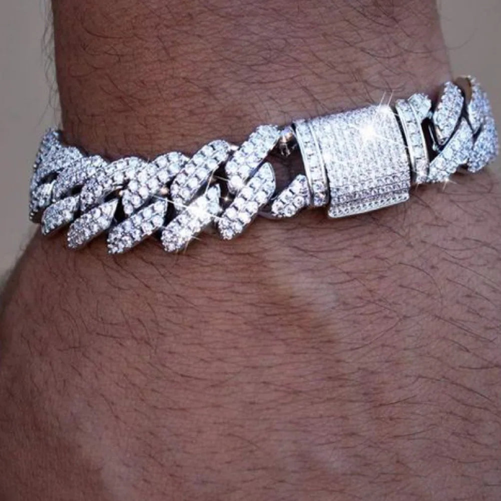 A close-up of a silver iced-out Cuban link bracelet featuring rhinestone pavé stones on a wrist.