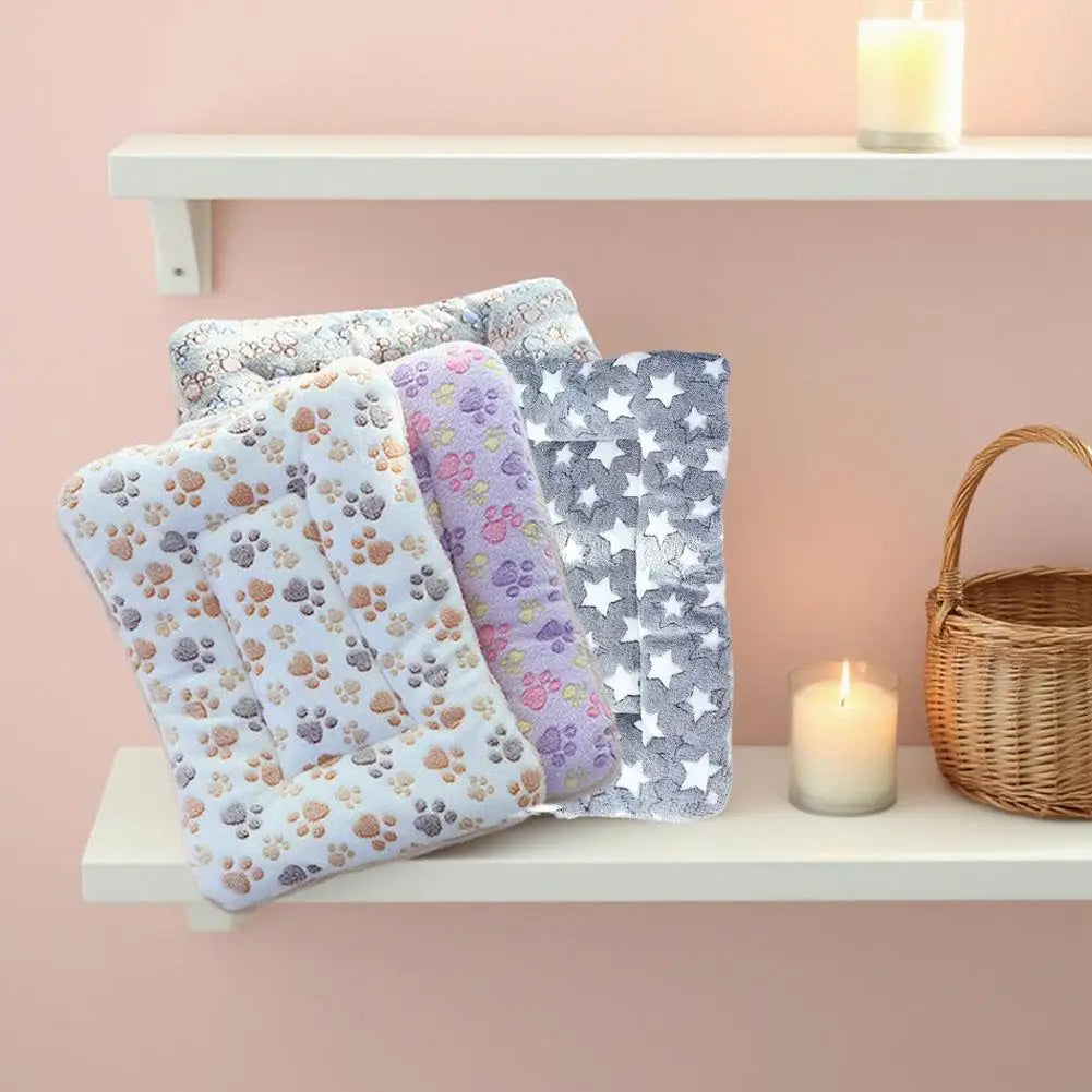 A stack of plush double-sided pet blankets featuring floral and star patterns displayed on a white shelf.