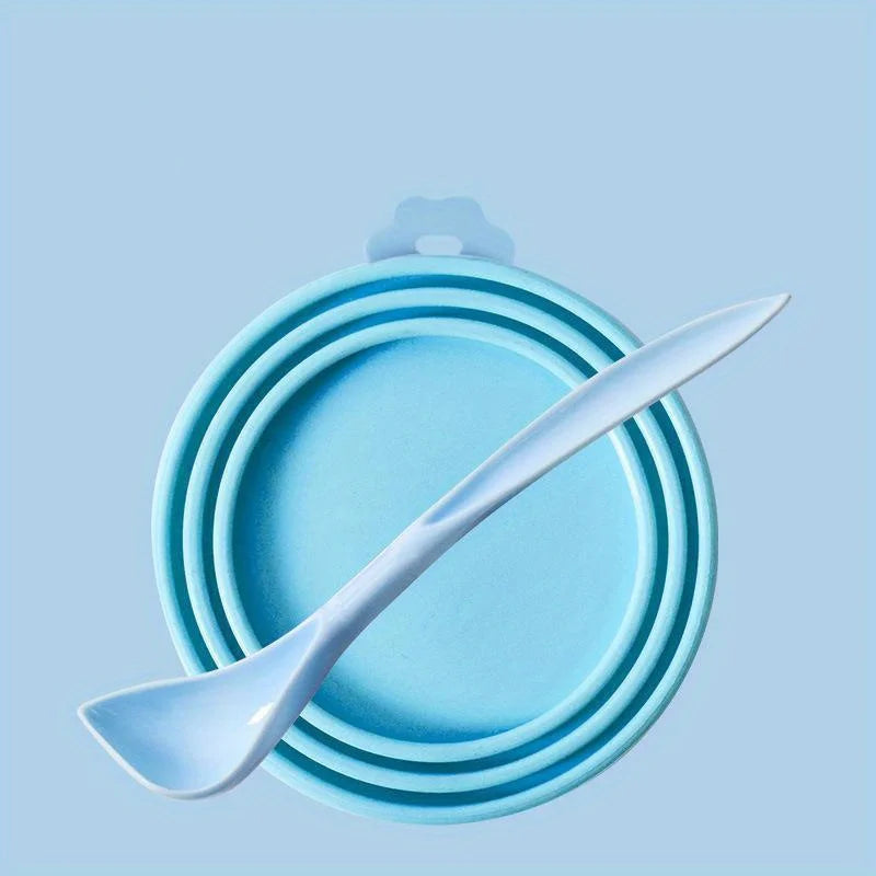 A light blue pet food can lid and spoon set resting on a pale blue background.