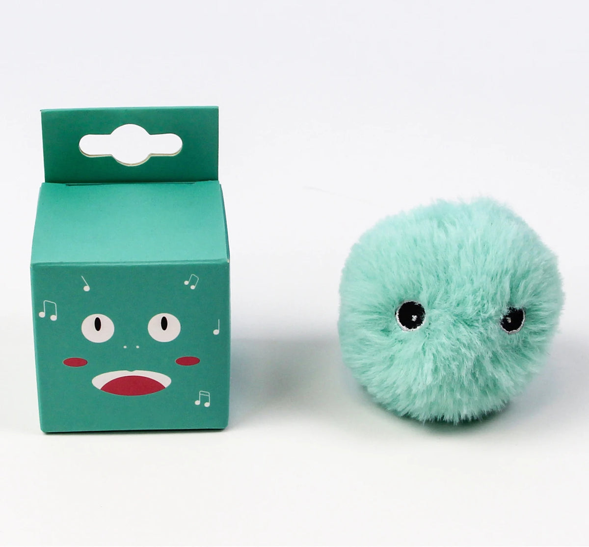 Une boîte en carton bleu sarcelle avec un visage de chat et une balle en peluche vert clair et moelleuse.
