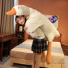 A young woman is posing with a large white plush goose body pillow in a cozy bedroom setting.