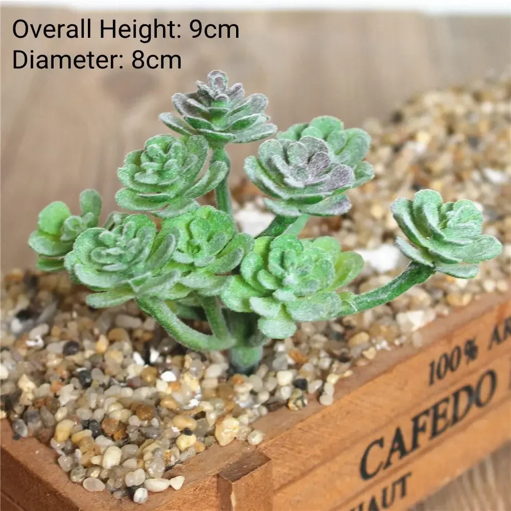 A flock artificial succulent plant with green and gray leaves is displayed in a wooden box with small pebbles.