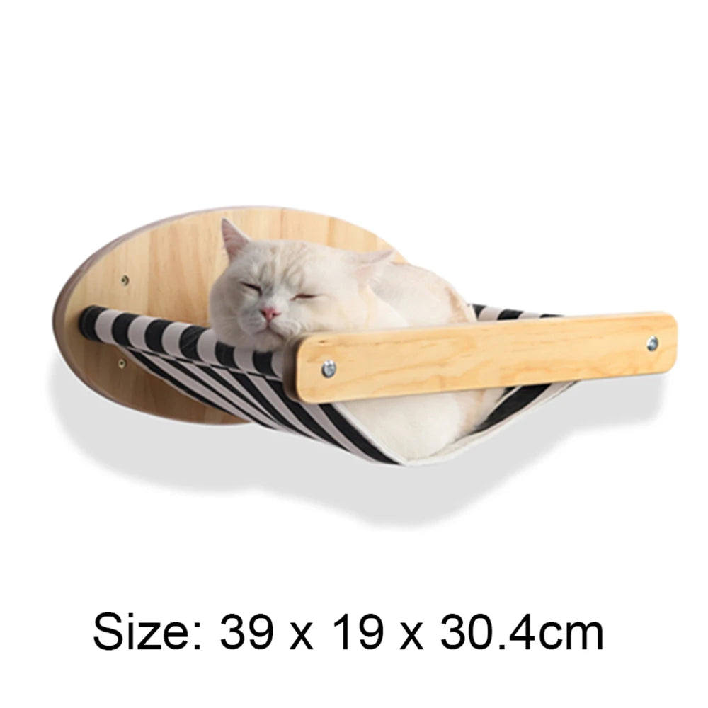 A fluffy white cat is relaxing in a wooden wall-mounted hammock or climbing frame with black and white stripes.