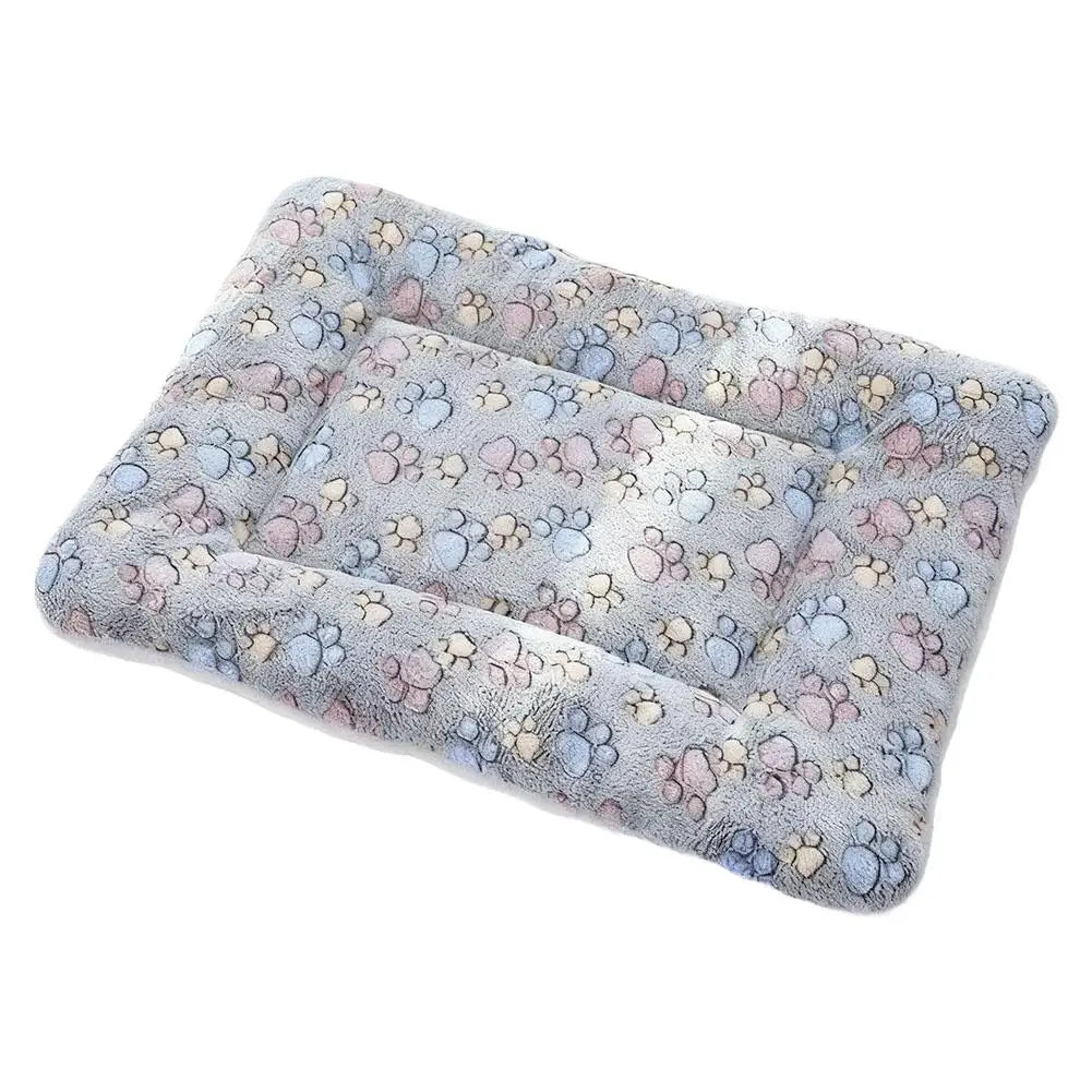A plush double-sided pet blanket mat with a soft, textured surface featuring paw prints in shades of blue and pink.