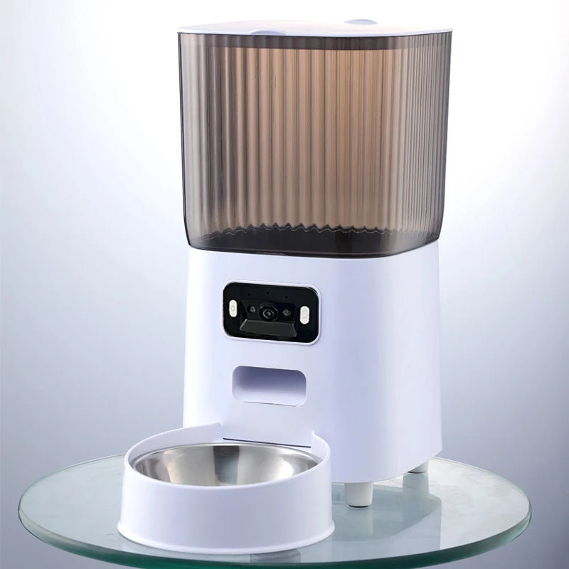 Comedero inteligente para mascotas blanco con tapa de cristal y sensor visible, sobre un soporte transparente.