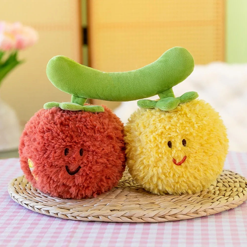 A close-up of soft plush vegetable dolls, including a red tomato and a yellow lemon, resting on a woven mat.