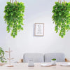 Künstliches Monstera-Blatt-Girlande hängt an einer weißen Wand über einem Holztisch.