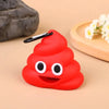 A bright red silicone dispenser shaped like a smiling face with black eyes and a clip, resting on a light wooden surface.