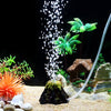 Aquarium decor featuring a simulated volcano, bubble stone, and an oxygenation tube with green aquatic plants.