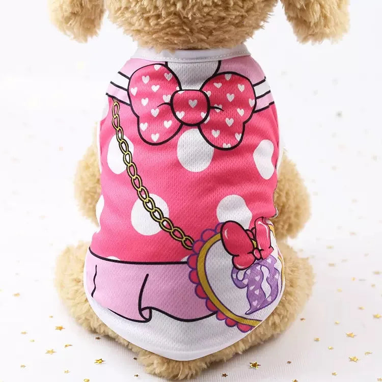 Un chien duveteux portant un gilet rose et blanc à motifs avec un grand nœud et des accents violets.