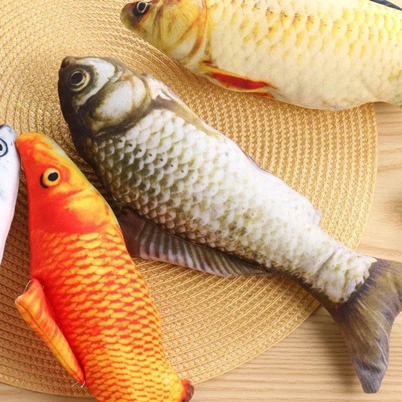 A collection of plush fish toys, including a large yellow fish and an orange fish, resting on a woven mat.