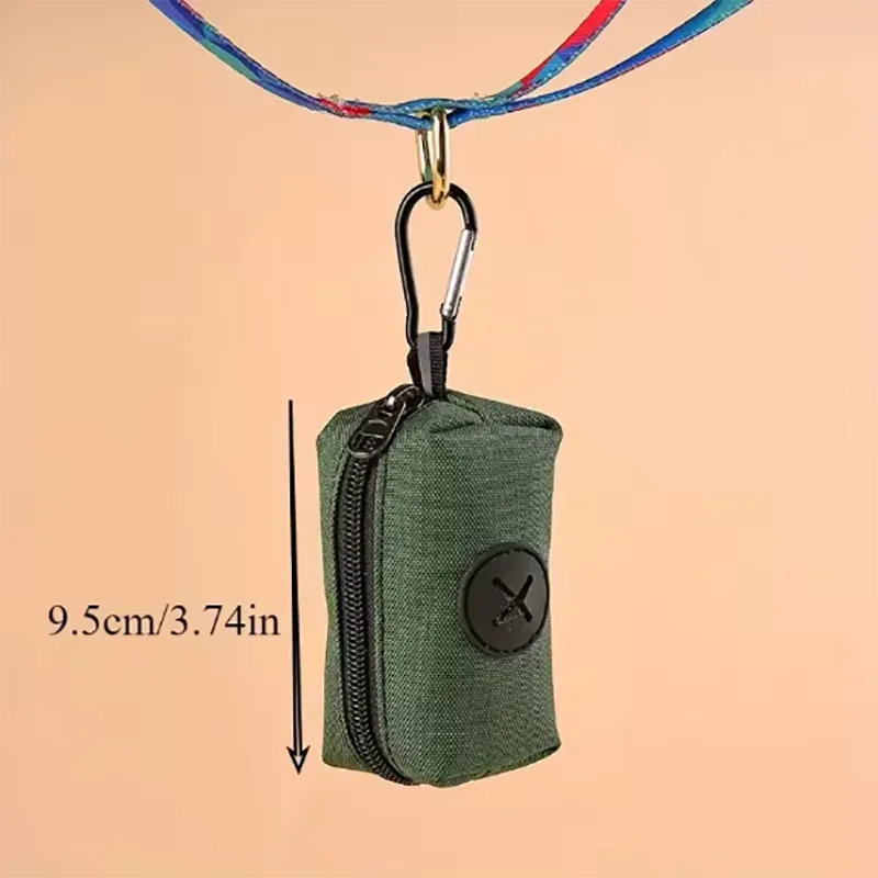 A dark olive green fabric poop bag dispenser attached to a metal carabiner clip.