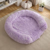 A round, fluffy lavender dog bed placed on a light beige rug in a bright room.