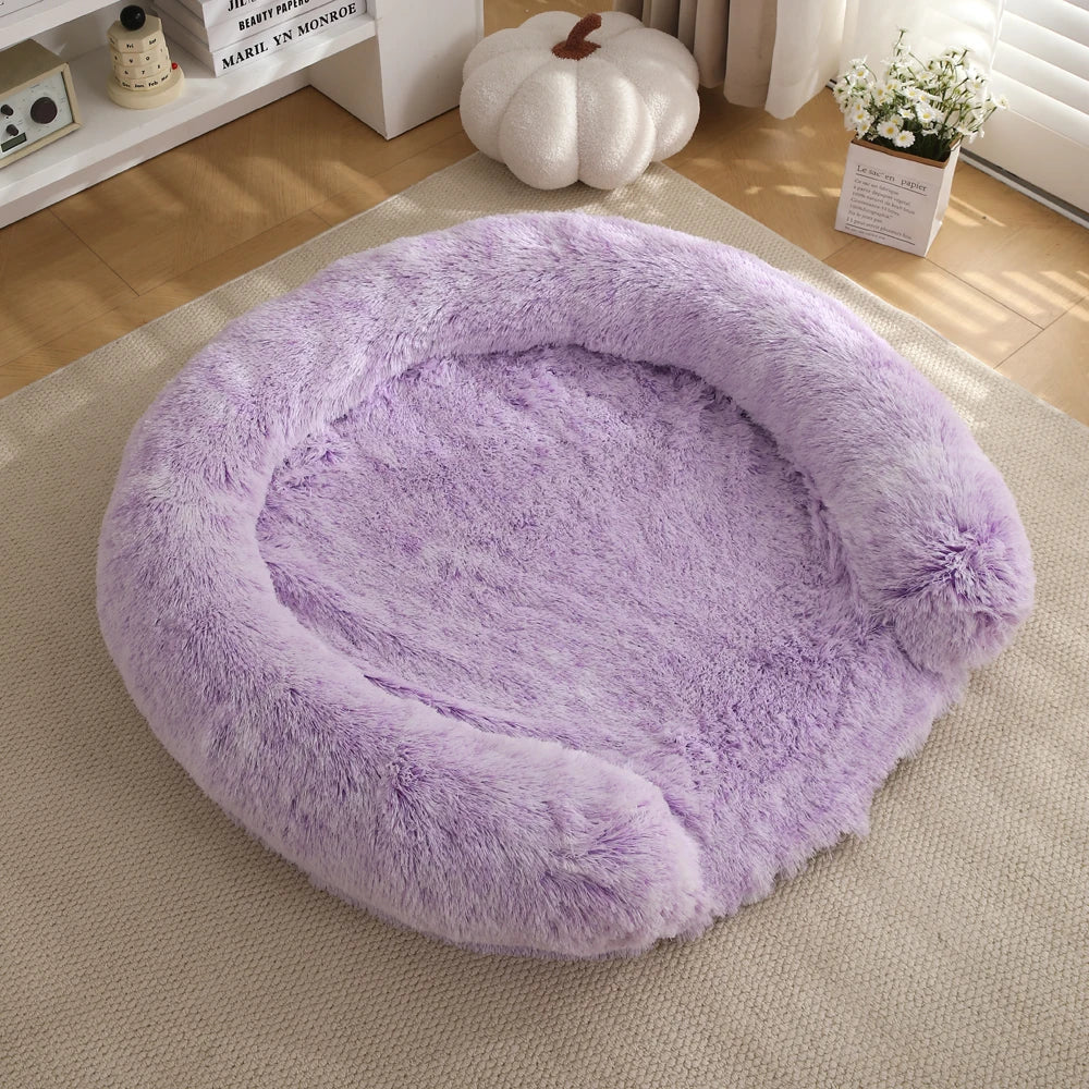A round, fluffy lavender dog bed placed on a light beige rug in a bright room.