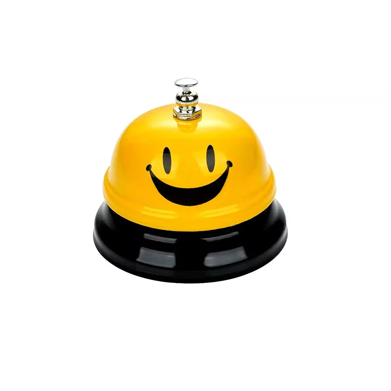 A yellow and black classic brass call bell with a smiling face.