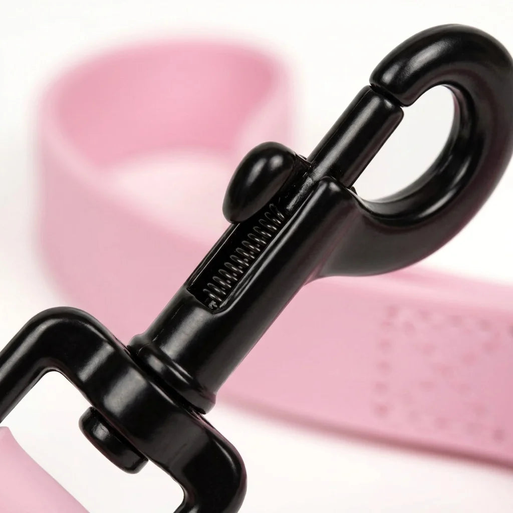 A close-up of a black waterproof PVC dog leash attached to a pink collar or strap.