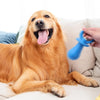 A happy golden retriever lying down with its mouth open and tongue out, next to a blue chew toy.