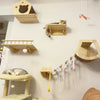 Wall-mounted wooden cat climbing hammocks and shelves displayed on a white wall.