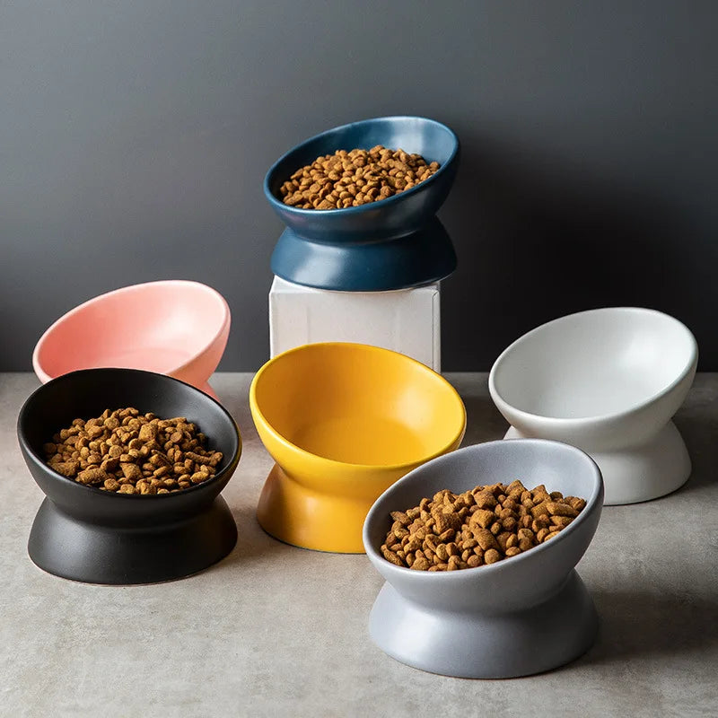 A collection of ceramic cat bowls in various colors and sizes, including blue, yellow, pink, and white.