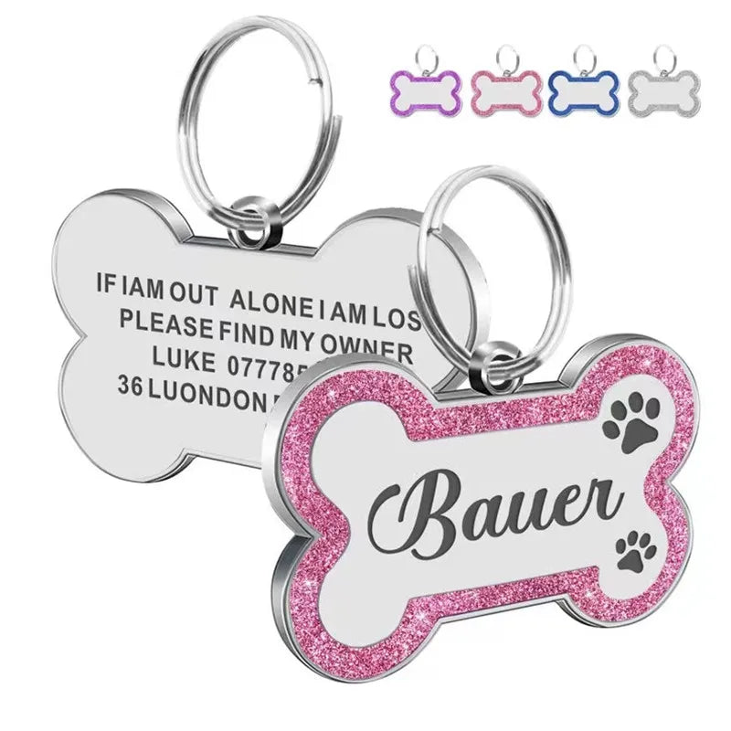 Silver and pink glitter pet ID tags with paw print designs and a custom name engraved on the tag