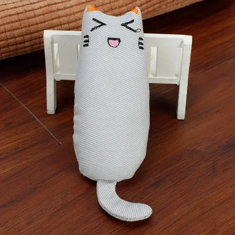 A gray knitted cat toy resembling a kitten with orange accents is resting on a white wooden surface.