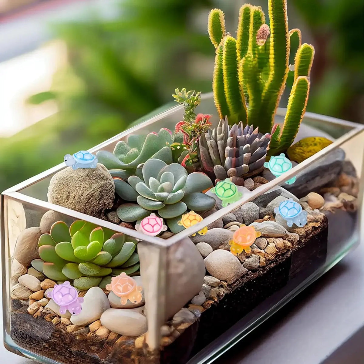 Glasterrarium mit kleinen Sukkulentenpflanzen und leuchtenden Harntier-Ornamenten für die Home-Dekoration