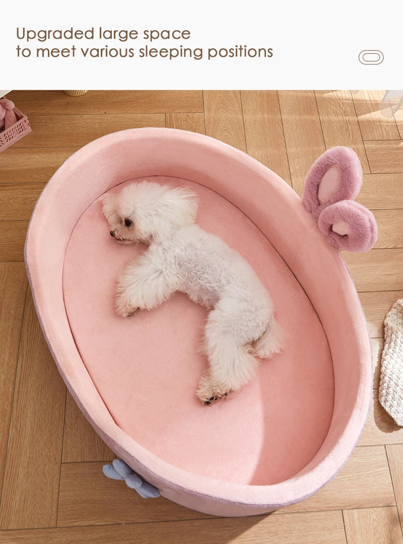 A pink plush pet bed is shown with a white fluffy dog lying inside on a wooden floor.