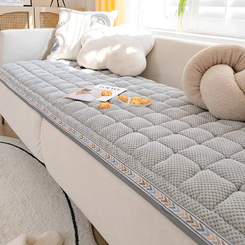 A cozy gray quilted fleece pet bed mat for dogs and cats resting on a light-colored sofa.