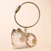 A clear glass cat charm keychain with a gold-colored leather cord and a metal clasp.