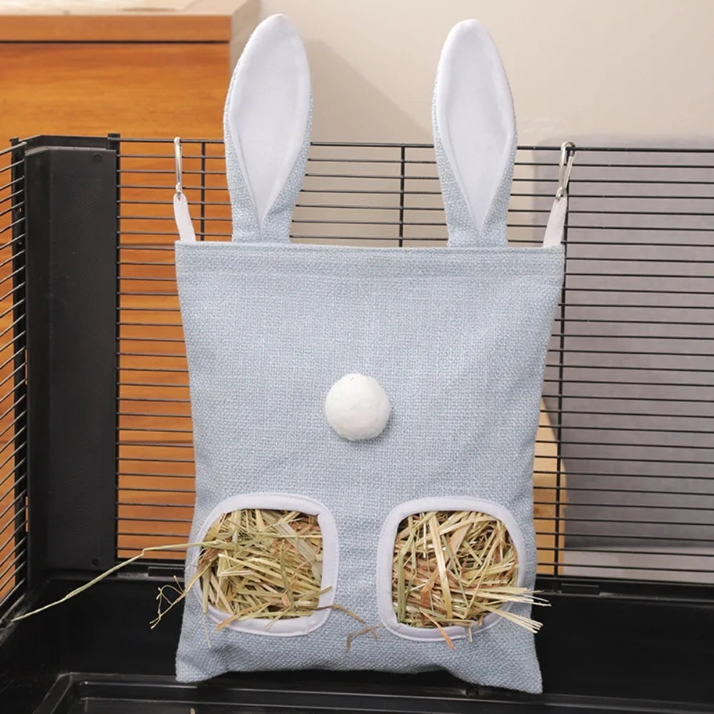 A light blue fabric bag with two oval openings for hay, used as a multi-hole hay feeder for small animals.