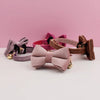 A collection of velvet cat collars in pink and mauve shades with black hardware displayed on a white surface.