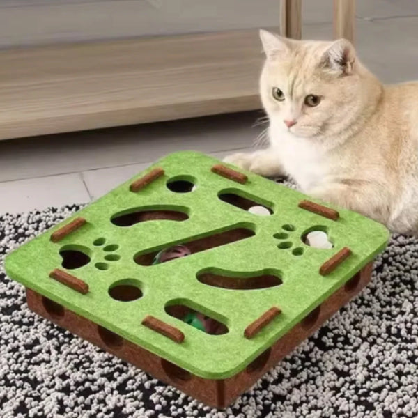 A green sisal cat scratching post with various holes and wooden elements, next to a light-colored cat.