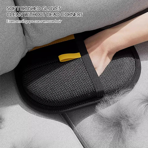 A close-up of a black pet hair removal glove with yellow accents resting on a gray fabric surface.
