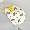 A white dog vest with a yellow collar and a pattern of gray bear prints on a light gray background.