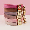 Stack of pink and mauve velvet cat collars with gold nameplates and bells