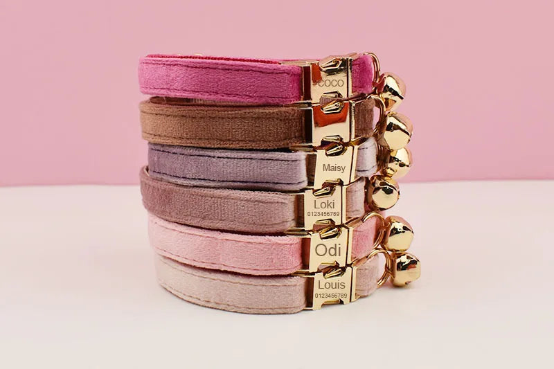 Stack of pink and mauve velvet cat collars with gold nameplates and bells