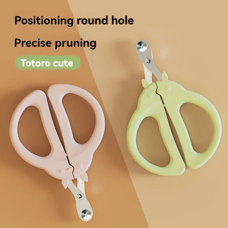 A pair of pink and yellow pet cat nail clippers with a safety guard shown on a wooden surface.